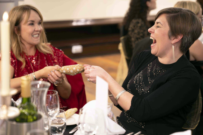 People at a christmas party pulling a christmas cracker